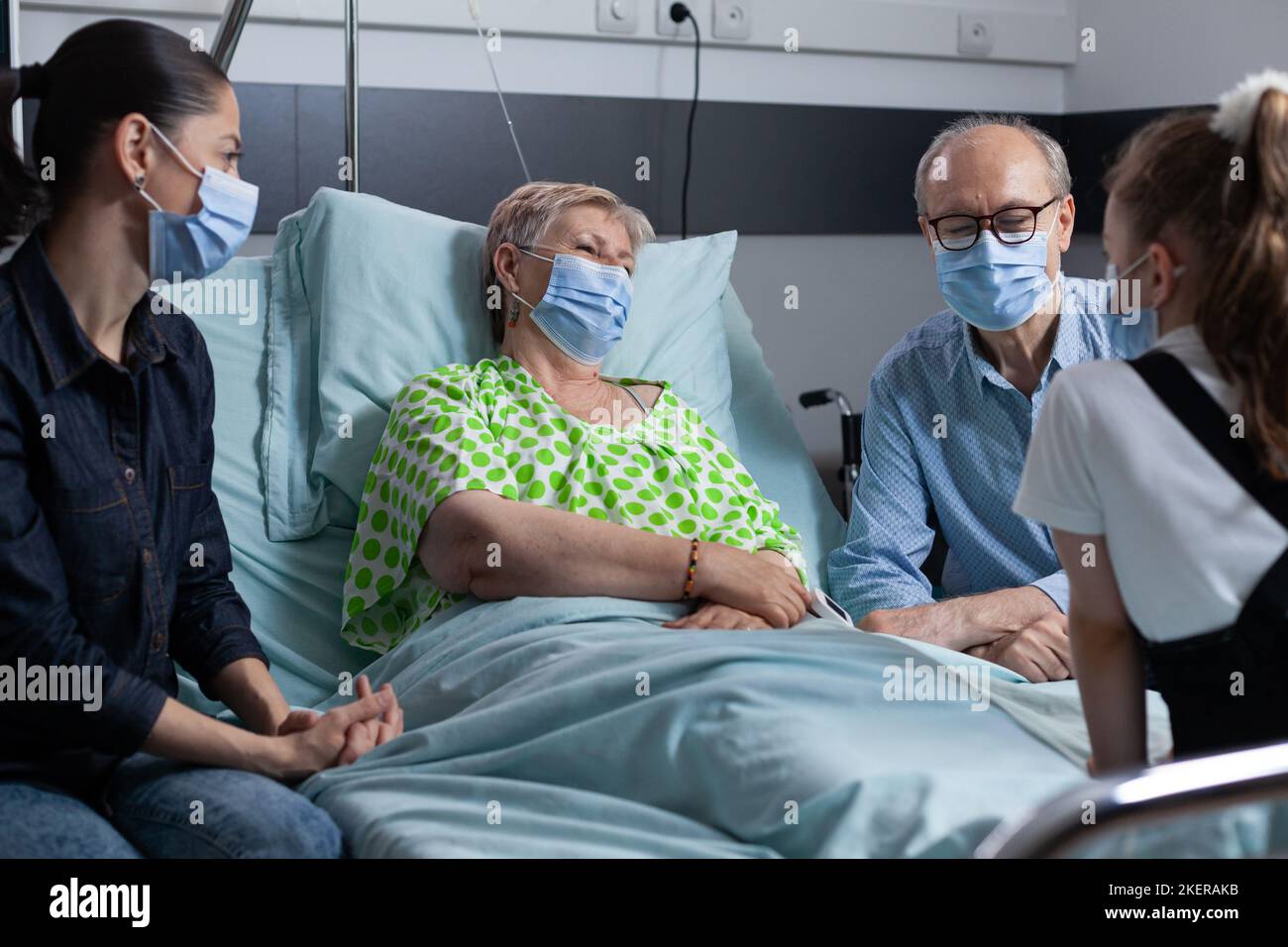 Family preventing spread of respiratory illnesses, enjoying time together, accompanying elderly woman in recovery at hospital. Old lady admitted to hospital for routine tests. Stock Photo