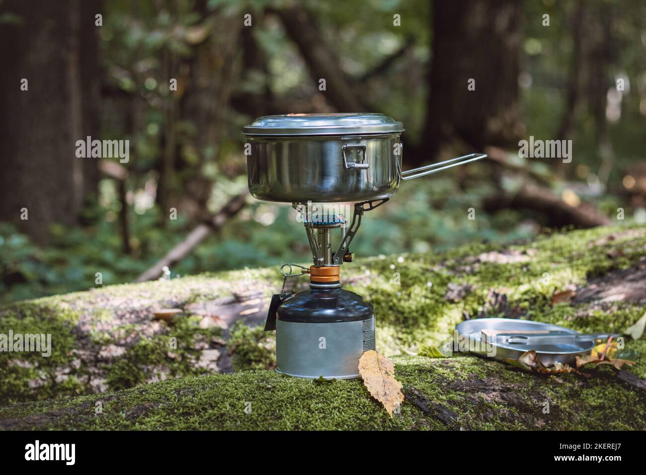 Boiling water for tea and food on a portable stove and in a stainless steel ultralight pot in the middle of the wilderness. Hiking lifestyle. Stock Photo