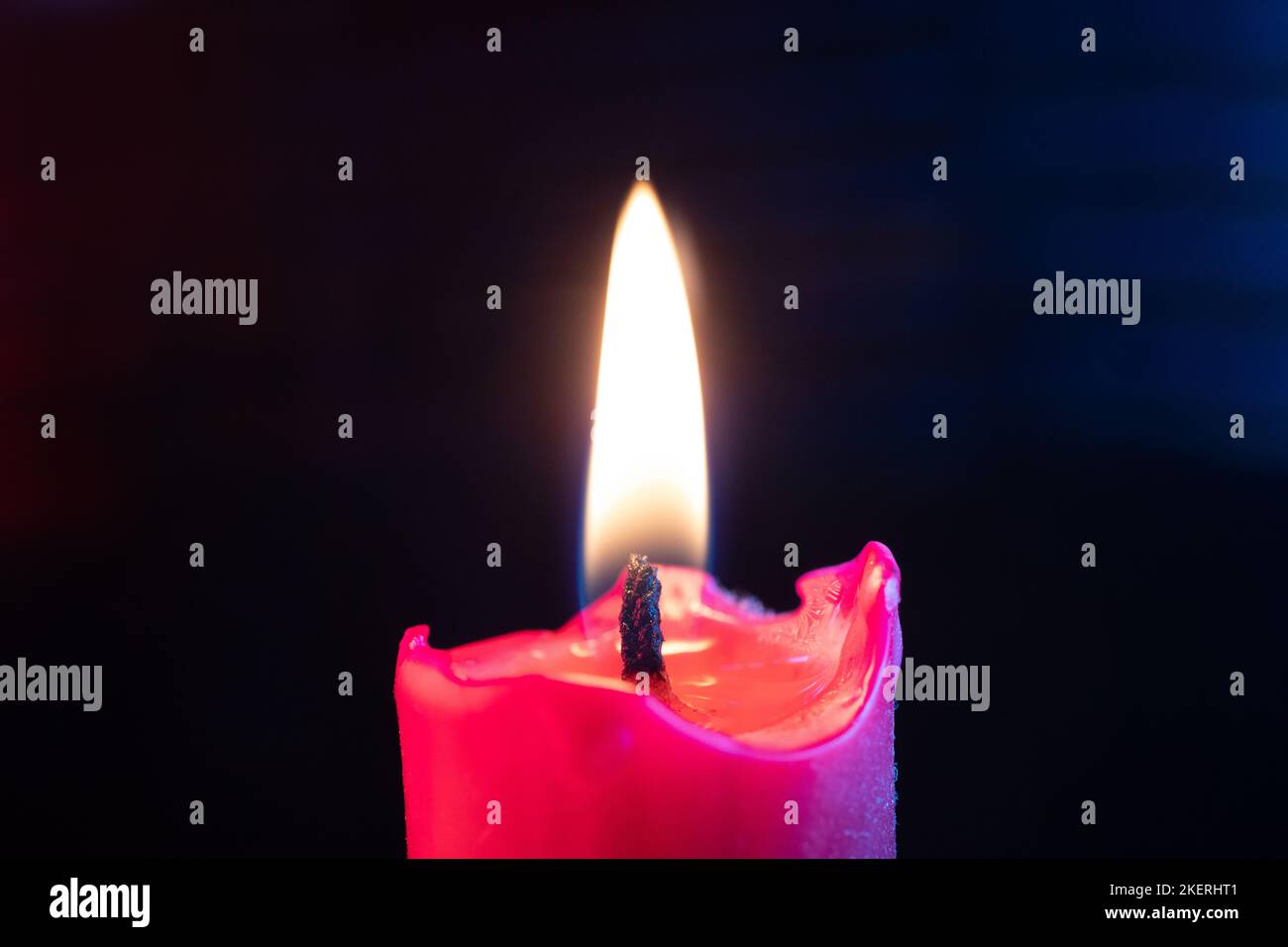 Candle flame flickers in the wind against a black background Stock Photo