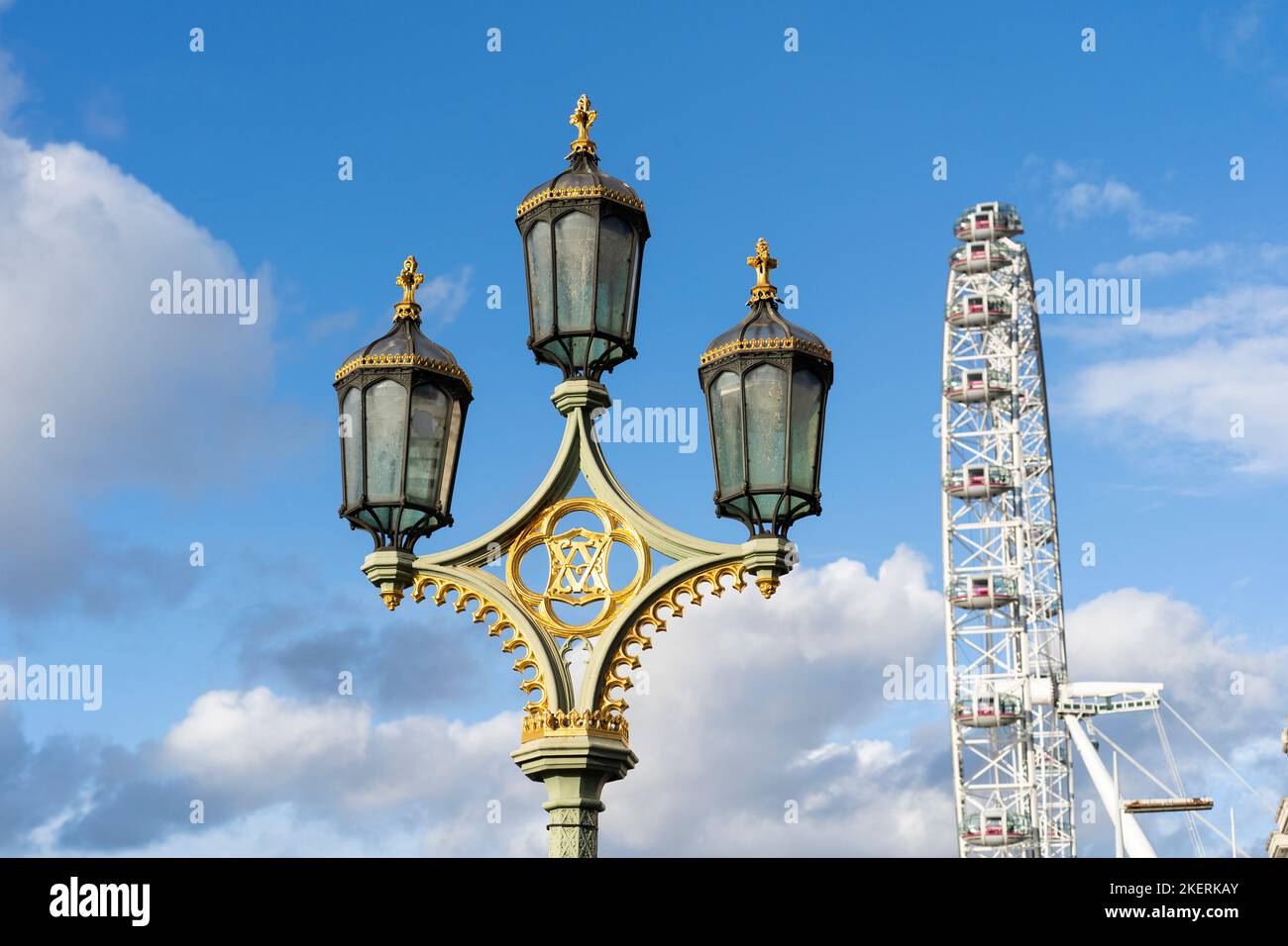 An ornate streetlight with three lanterns on Westminster Bridge, with the London Eye behind. The bridge links Westminster with Lambeth. England Stock Photo