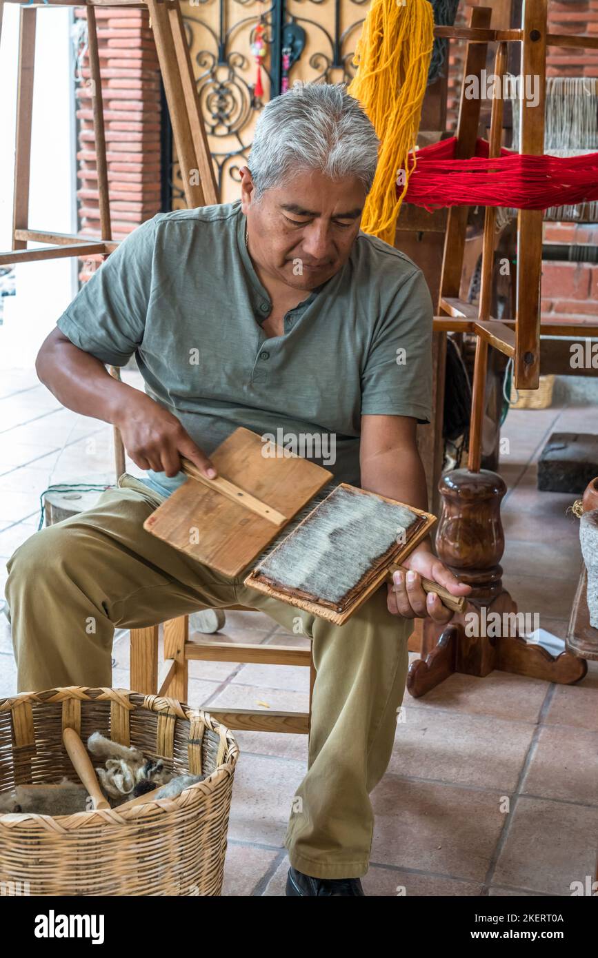 Master weaver Jeronimo Vazquez G. demonstrates carding wool by hand before spinning into yarn for weaving rugs.  Teiotitlan del Valle, Oaxaca, Mexico. Stock Photo