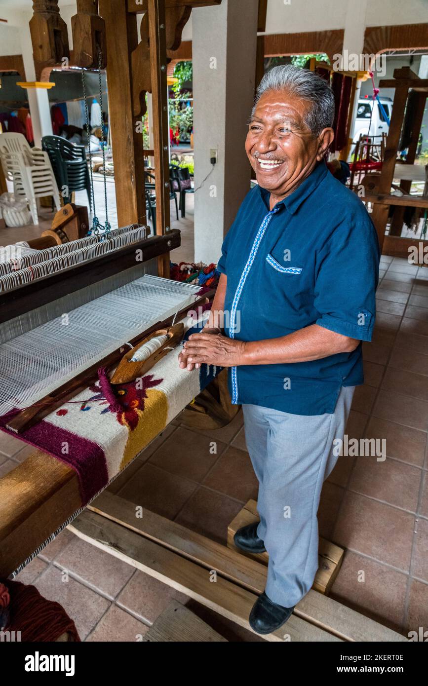 A master weaver weaves a woolen rug on a wooden foot treadle loom in
