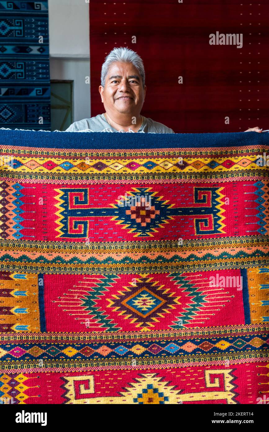 Master weaver Jeronimo Vasquez G. with a woolen rug in the family weaving business in Teotitlan, Oaxaca, Mexico.  The yarn is dyed with all natural dy Stock Photo