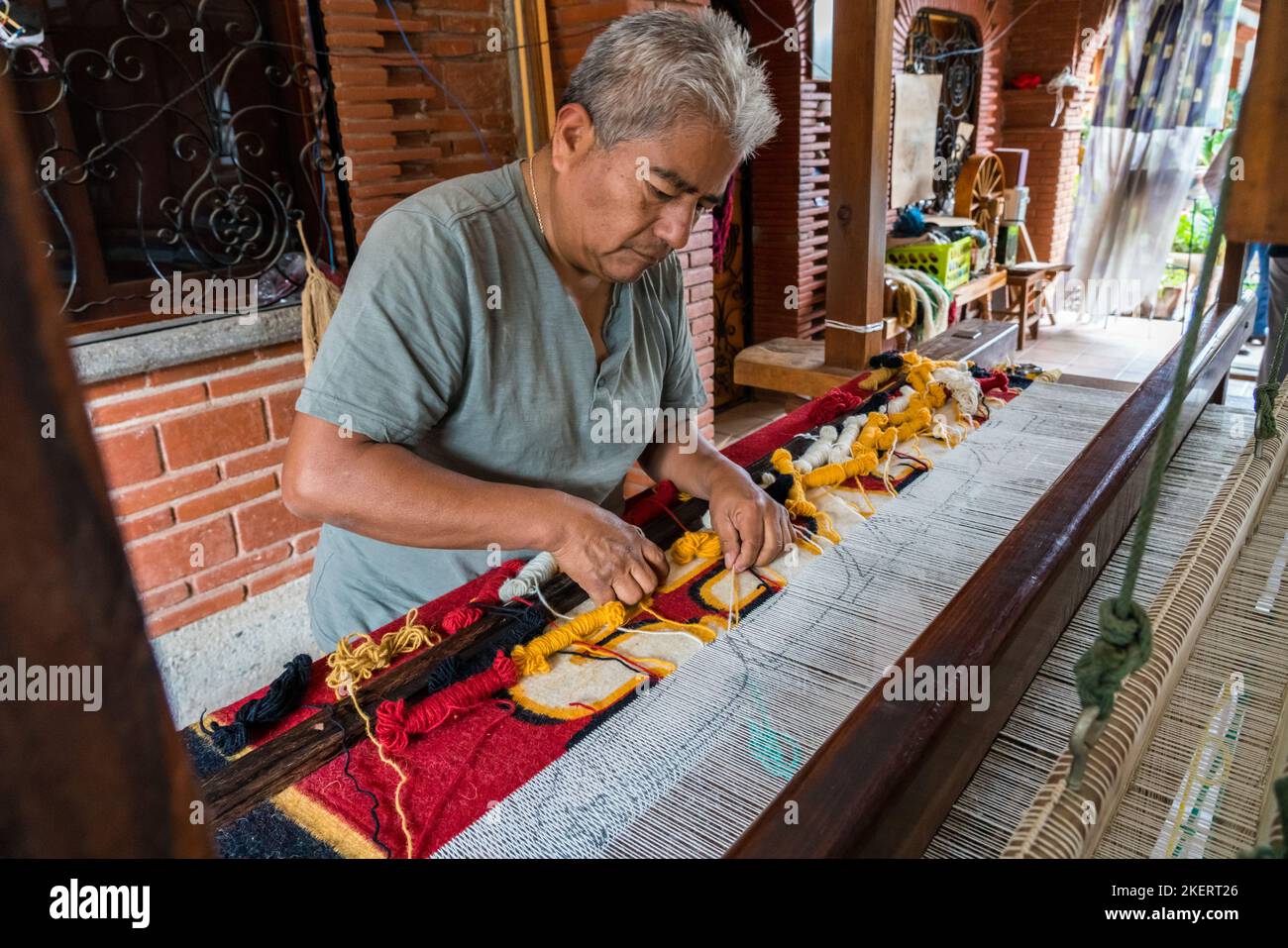 A master weaver weaves a woolen rug on a wooden foot treadle loom in
