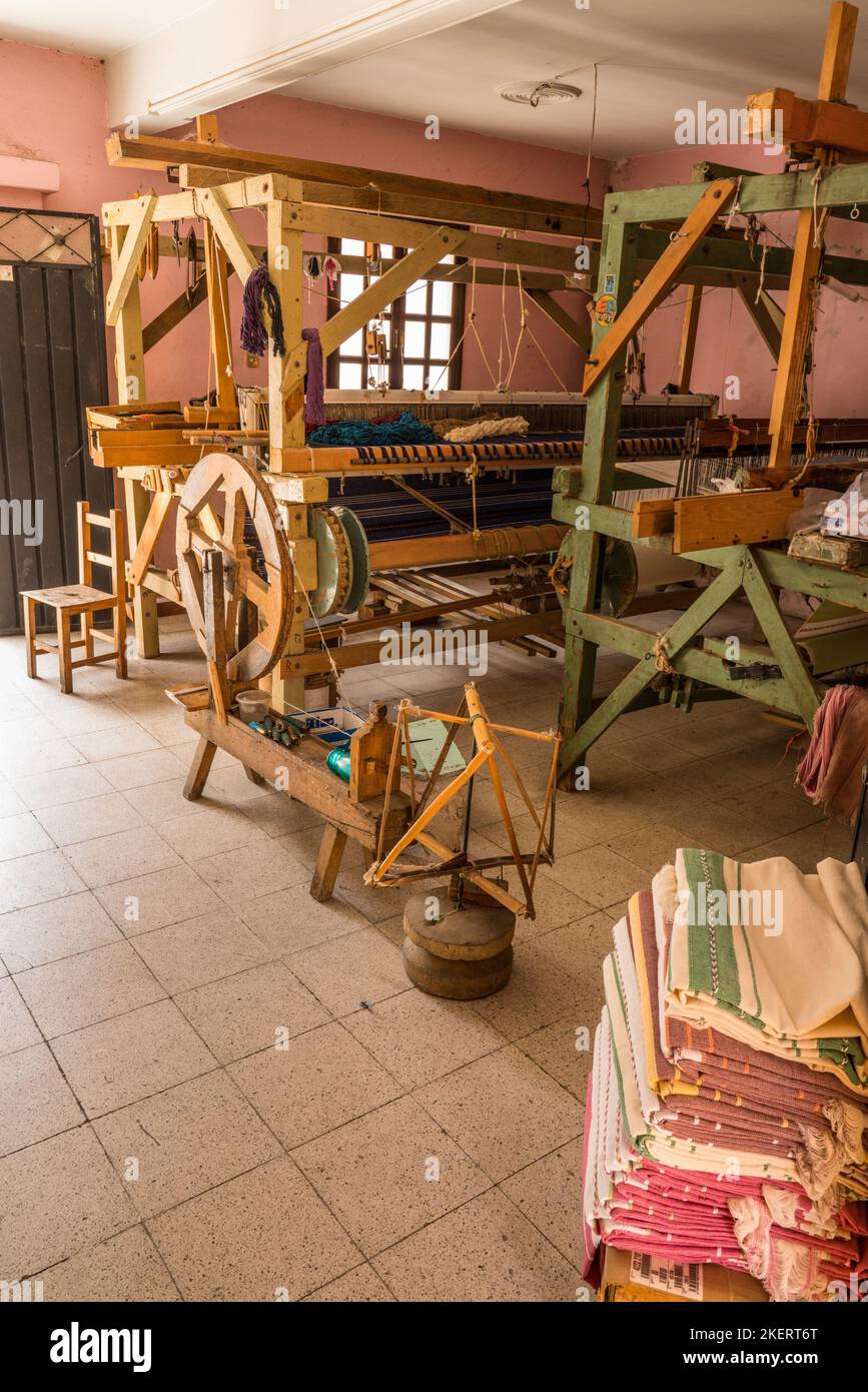 A wooden spinning wheel and foot loom in a home weaving in