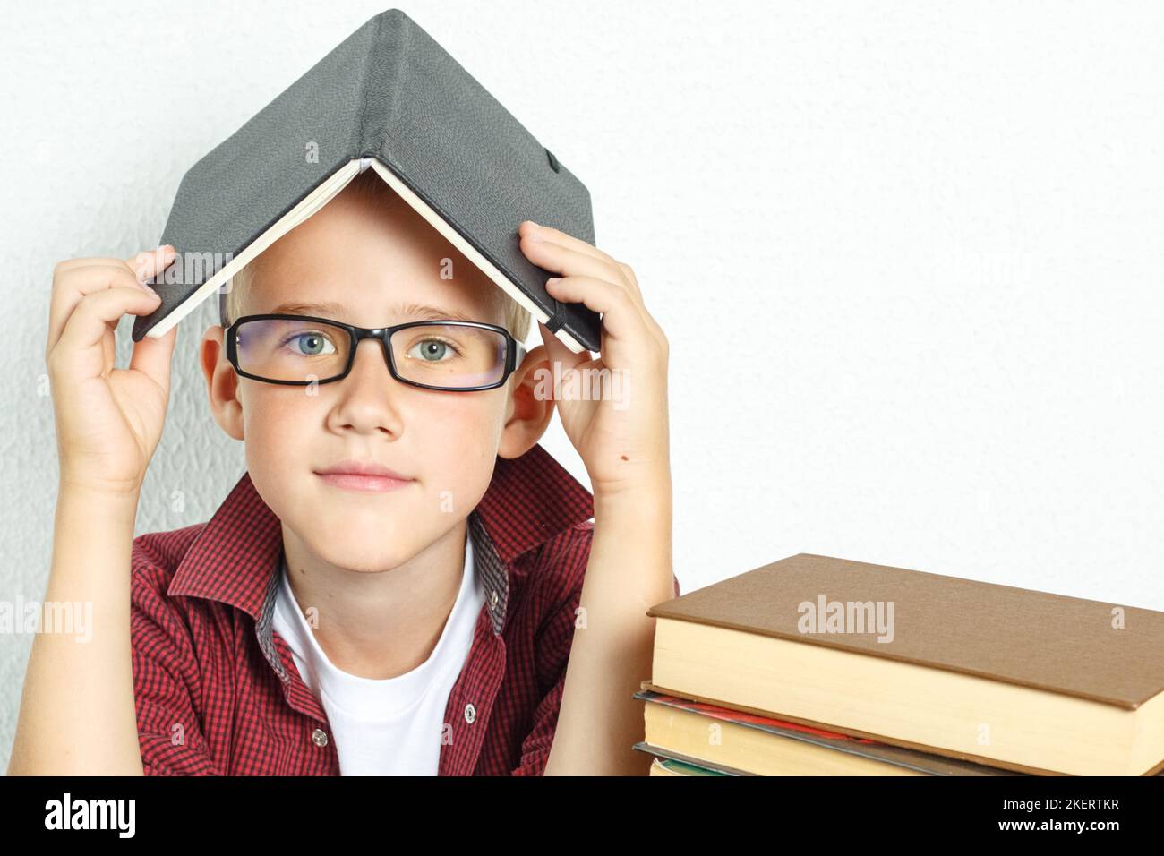 Education concept. A pupil boy sits at a table with books, holding an ...