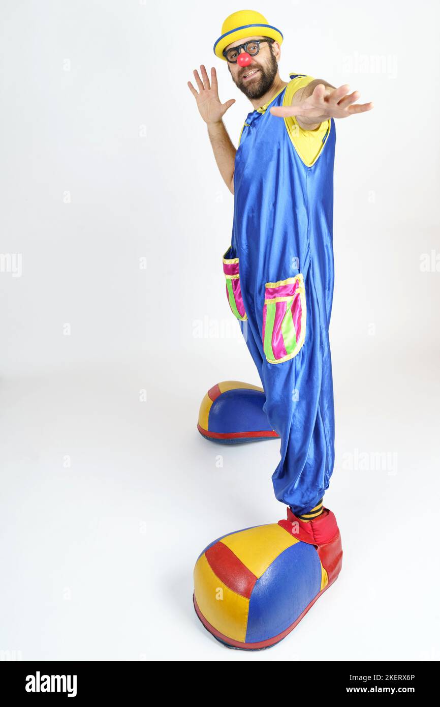 Holiday concept. A clown in a bright blue and yellow suit, glasses and ...