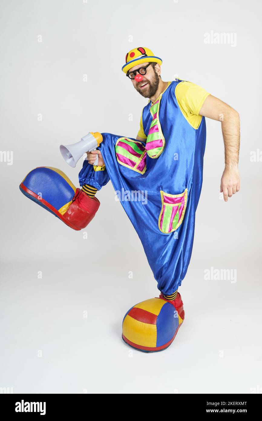 Holiday concept. A clown in a bright blue and yellow suit, glasses and ...