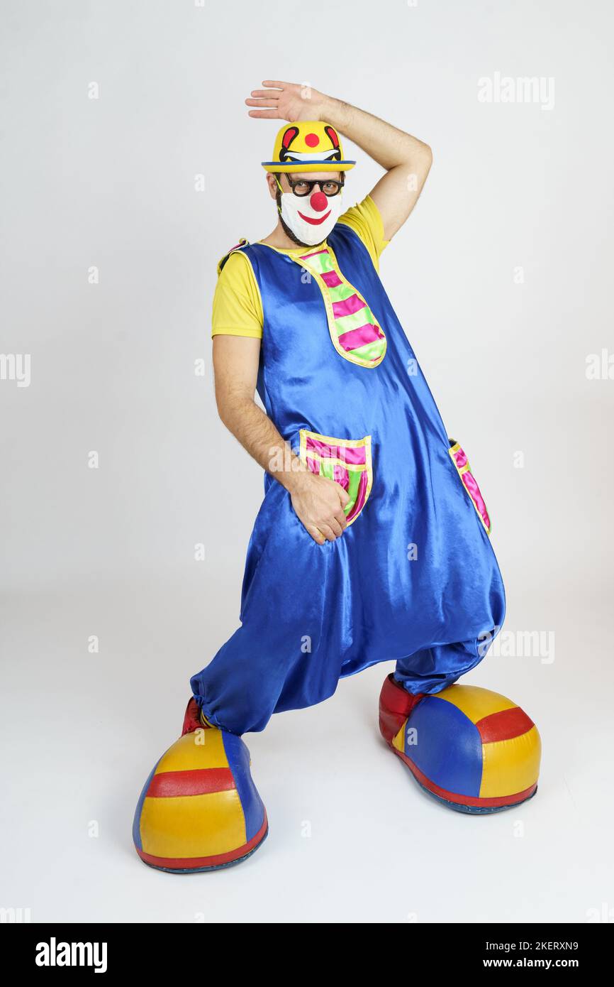 Holiday concept. A clown in a bright blue and yellow suit, glasses and ...