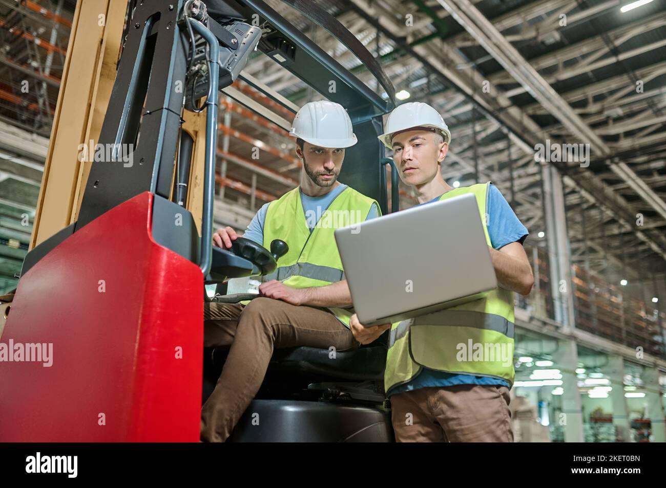 Men in protective helmets working in a storage area Stock Photo