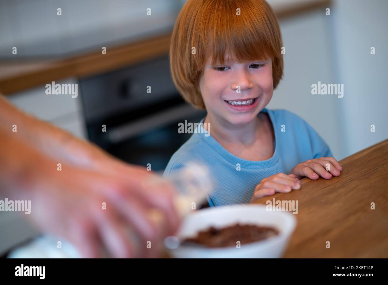 Man pouring milk into the plate of his son Stock Photo