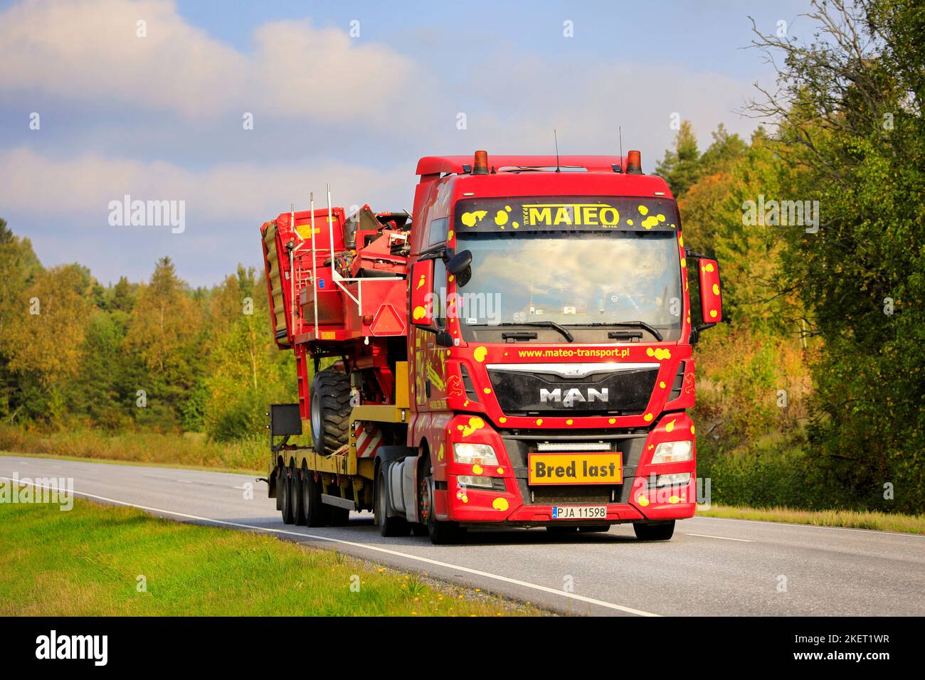 Colorful MAN TGX truck of Mateo Transport hauls Grimme SE 75-30 potato harvester as wide load on a beautiful day of autumn. Salo, Finland. Sept 25, 20 Stock Photo