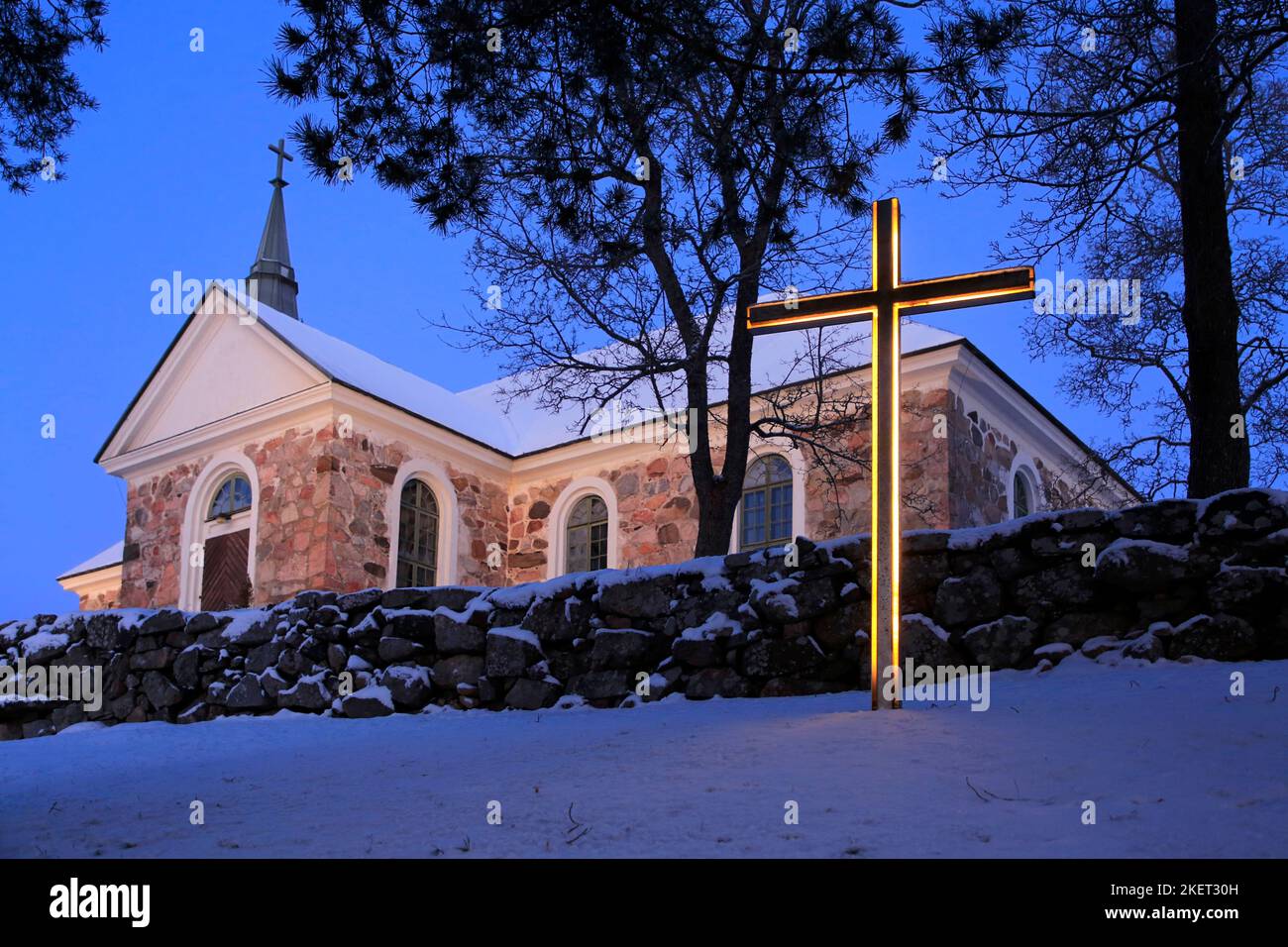 Illuminated cross in front of Uskela Church, built 1832 and designed by the famous Finnish architect C. L. Engel, in Christmas Day twilight. Salo, Fin Stock Photo