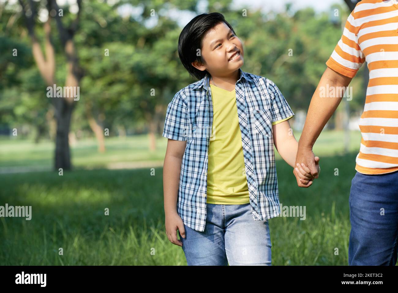 Portrait shot of cute little boy in casualwear holding hands with his ...