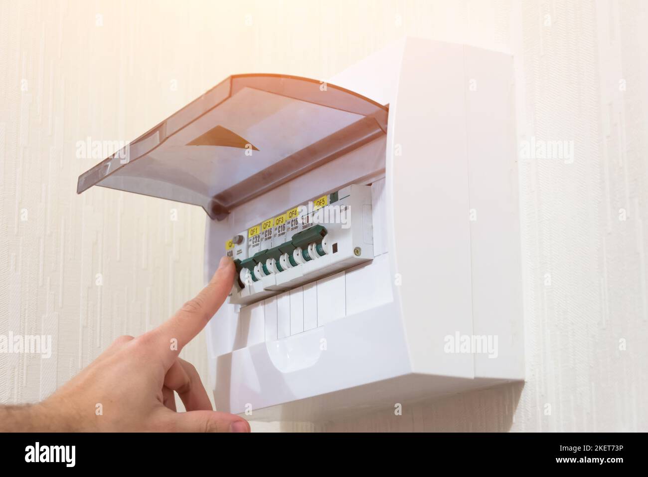 Circuit breaker board displays many switches. A finger is about to turn it back on Stock Photo