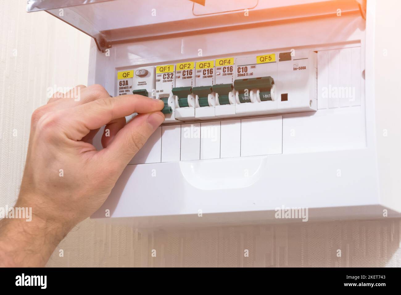 Circuit breaker board displays many switches. A finger is about to turn