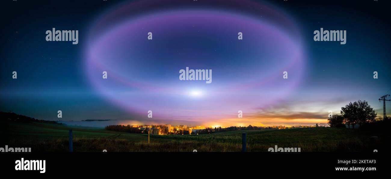lunar halo in the night sky and city light on the horizon Stock Photo