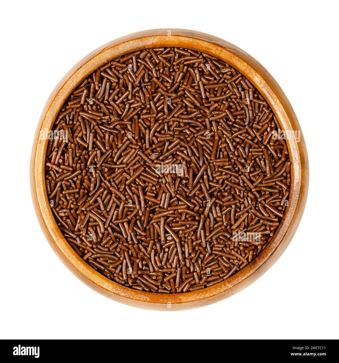 Milk chocolate sprinkles, in a wooden bowl. Tiny candies, also known as vermicelli, or as hundreds and thousands. Very small pieces of confectionery. Stock Photo