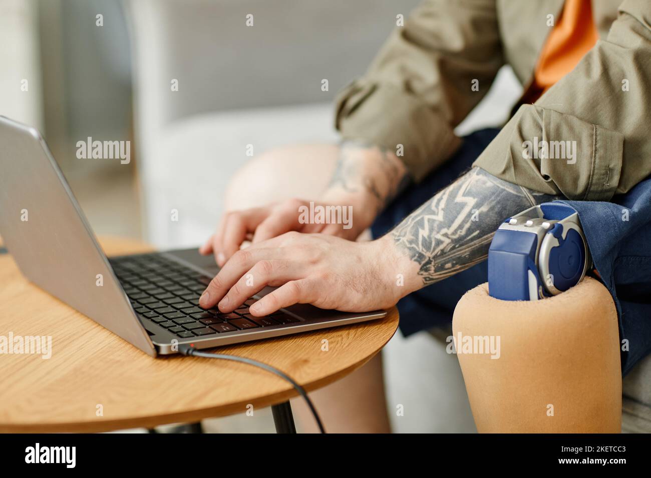 Closeup of man with prosthetic leg using laptop while working, copy space Stock Photo