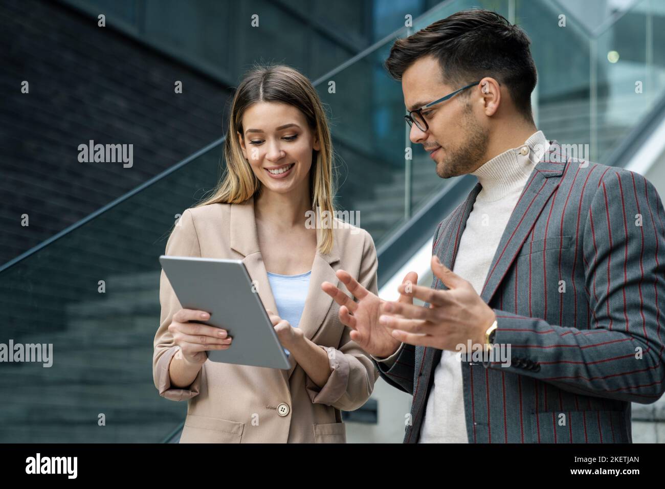 Successful young business people talking, working together in front of modern business building Stock Photo