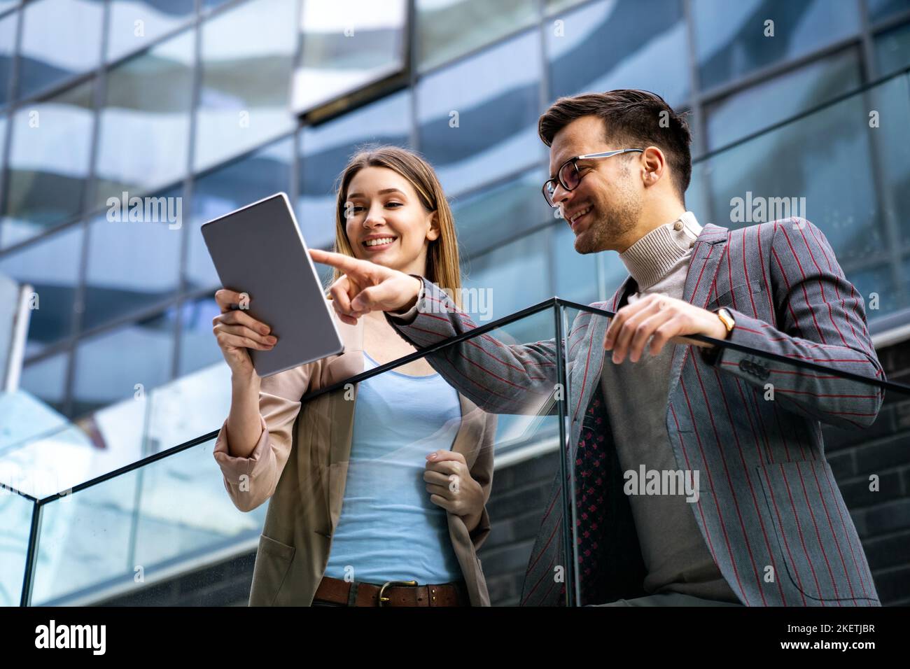 Successful young business people talking, working together in front of modern business building Stock Photo