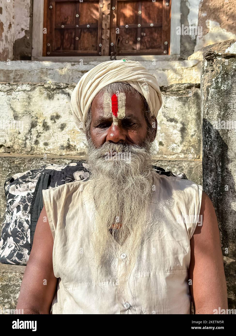 Pushkar, Rajasthan, India - November 2022: Portrait of an old  sadhu baba on the street of Pushkar in traditional saffron dress with white beard. Stock Photo