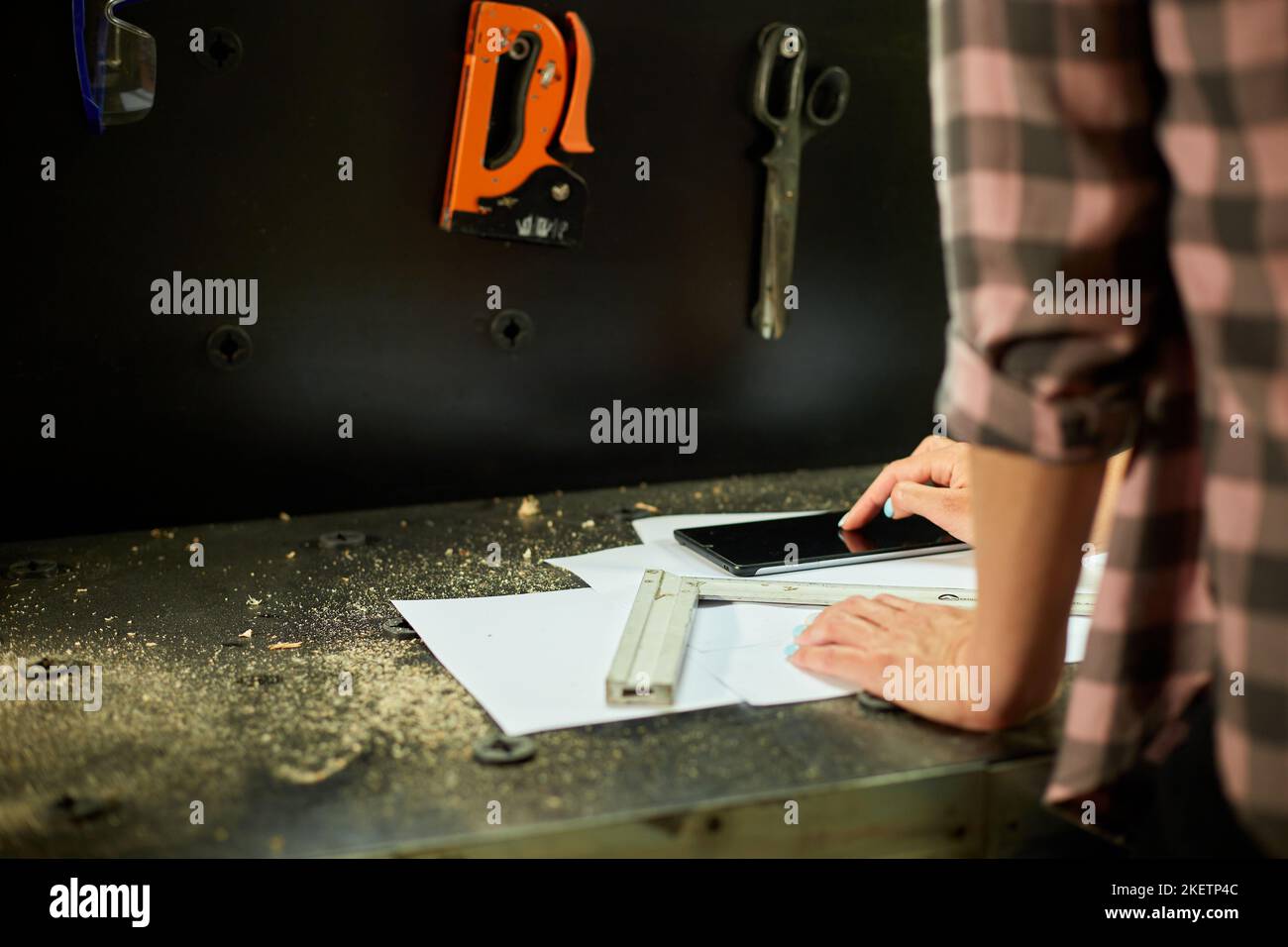 Female business owner using digital tablet in workshop, industrial woman engineer working with blueprints and tablet in the workshop. Stock Photo