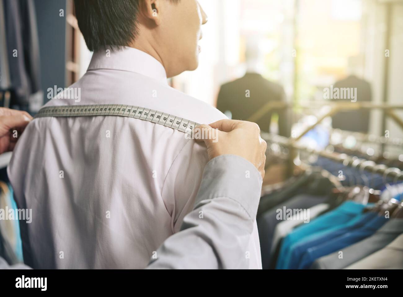 Tailor measuring shoulder width of male client Stock Photo Alamy