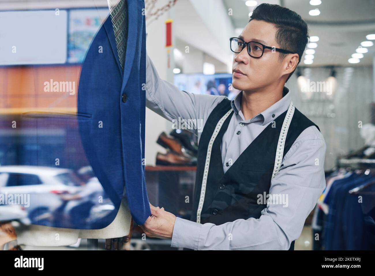 Professional Vietnamese tailor putting blue suit on mannequin Stock