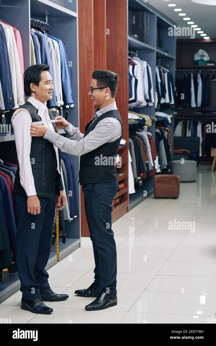 Happy tailor measuring jacket on male client Stock Photo