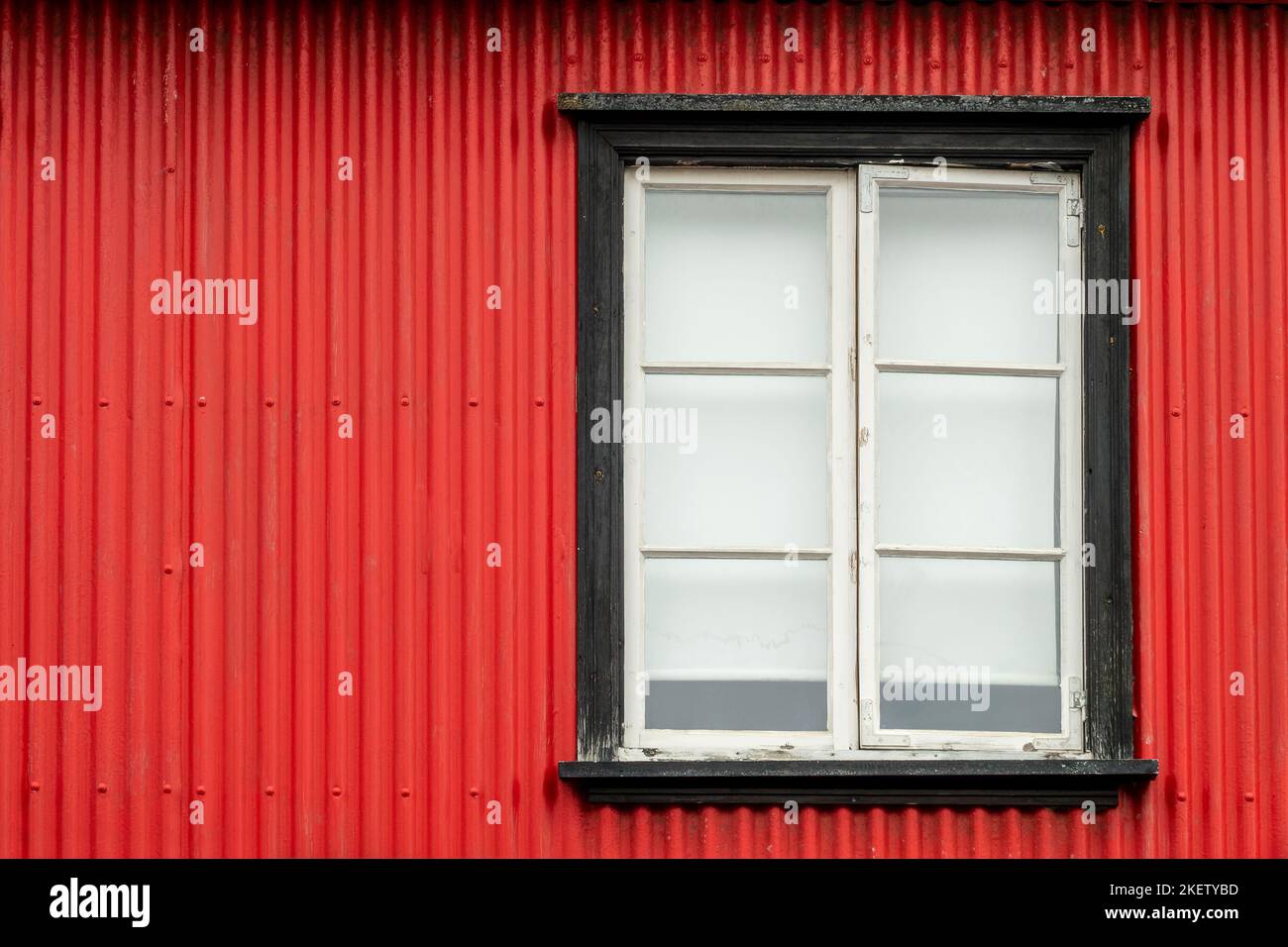 Window on a red painted wall, colorful house, architecture detail in Reykjavik, Iceland Stock Photo