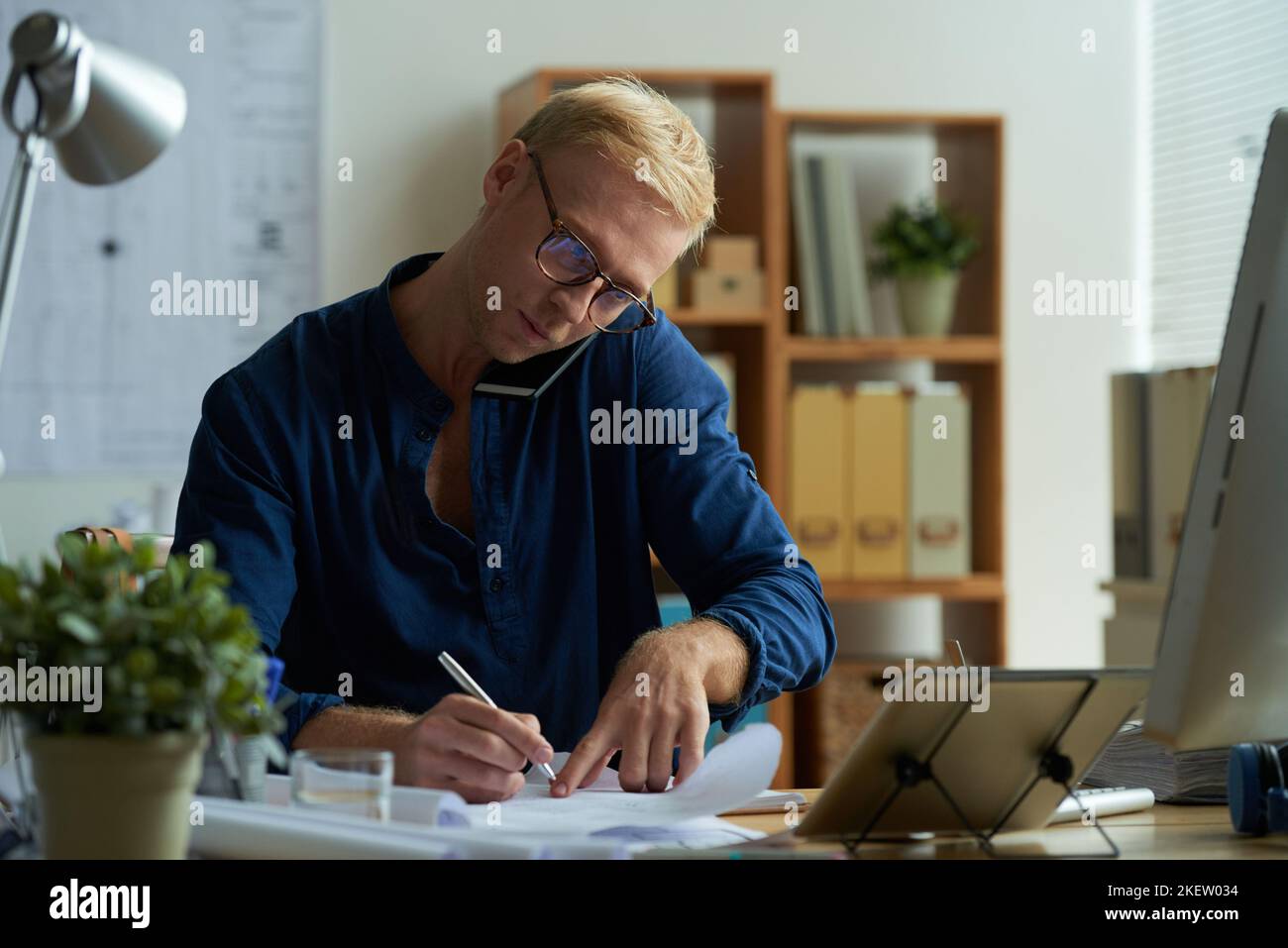 Engineer taking notes when talking to client on the phone Stock Photo