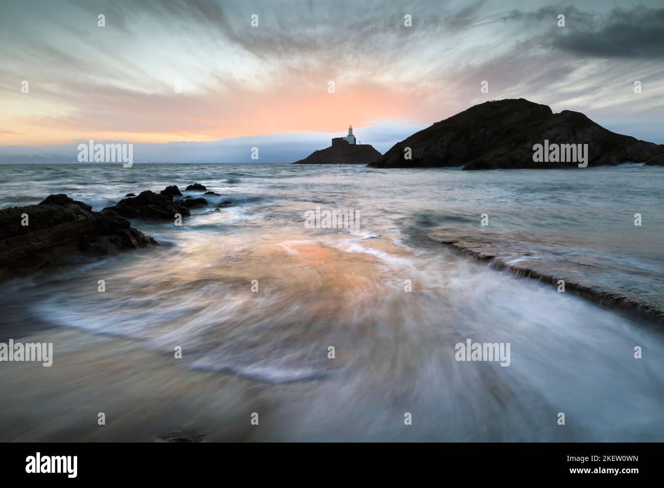 Sunrise over Mumbles lighthouse in Swansea Bay, South Wales UK Stock Photo