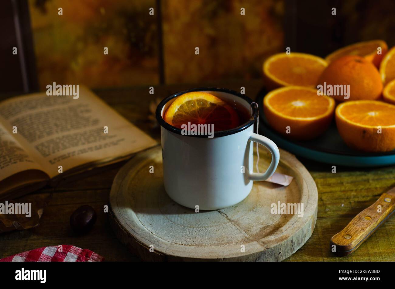 Cup of autumn tea with a book and yellow dry leaves near a window, copy space. Hot drink for autumn cold rainy days. Hygge concept, autumn mood. Stock Photo