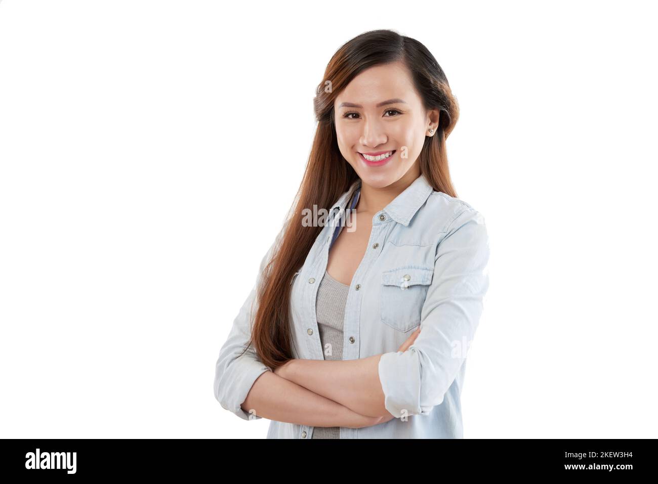 Portrait of smiling young Asian woman standing with her arms cropped ...