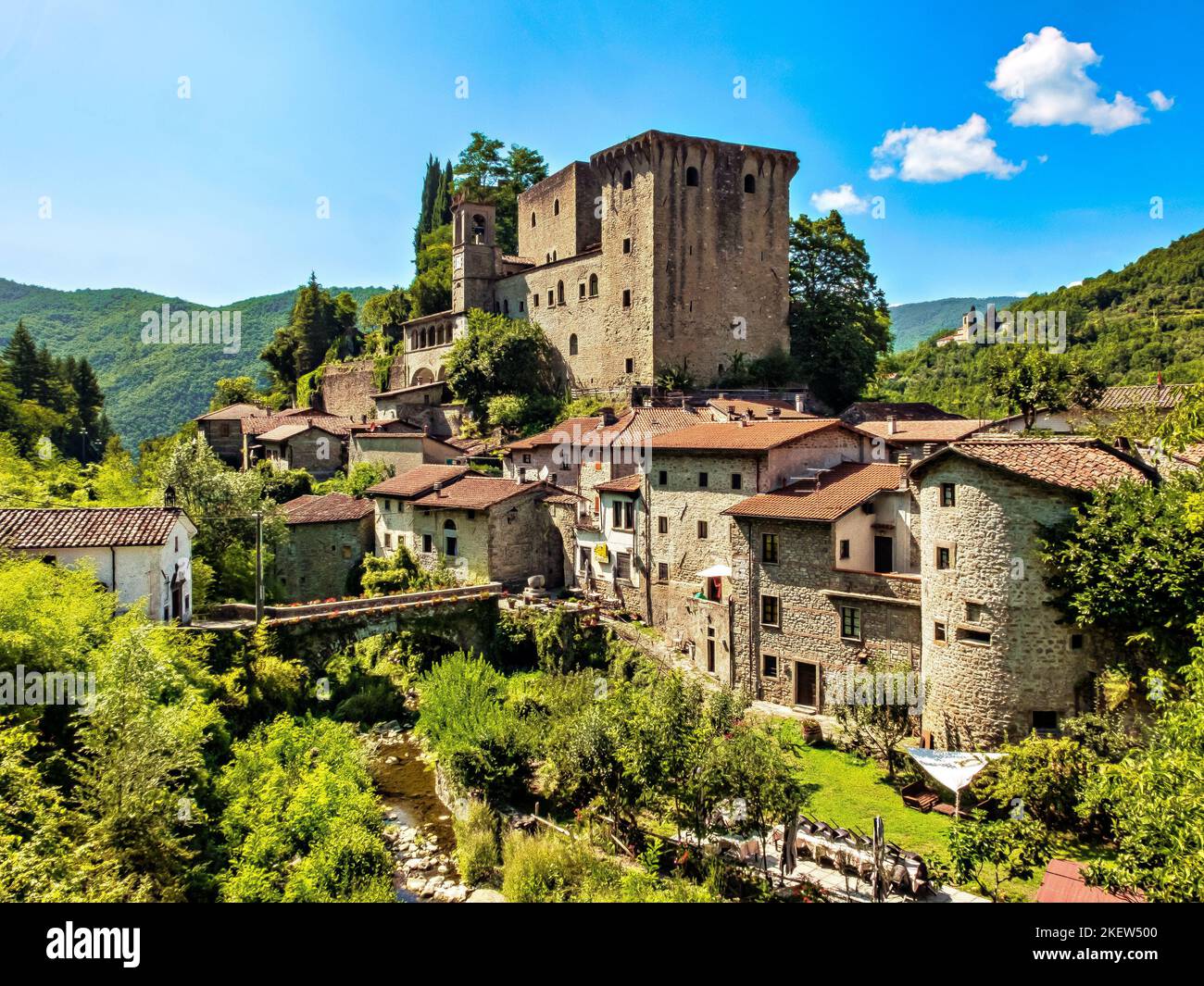 Medieval fortress of Verrucola in Tuscany, Italy, on the green hills of Lunigiana, in Toscana, Italy, with stone bridge crossing a stream. Stock Photo