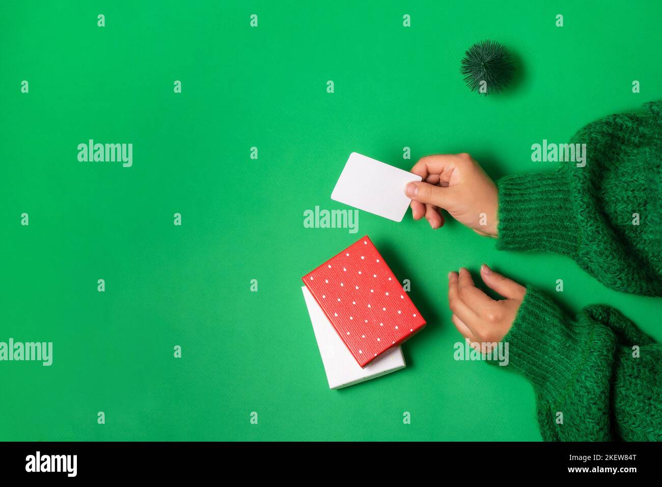 Female hands holding a bonus or credit bank card template for paying for the purchase of gifts in boxes Concept of online shopping and holiday sales. Stock Photo