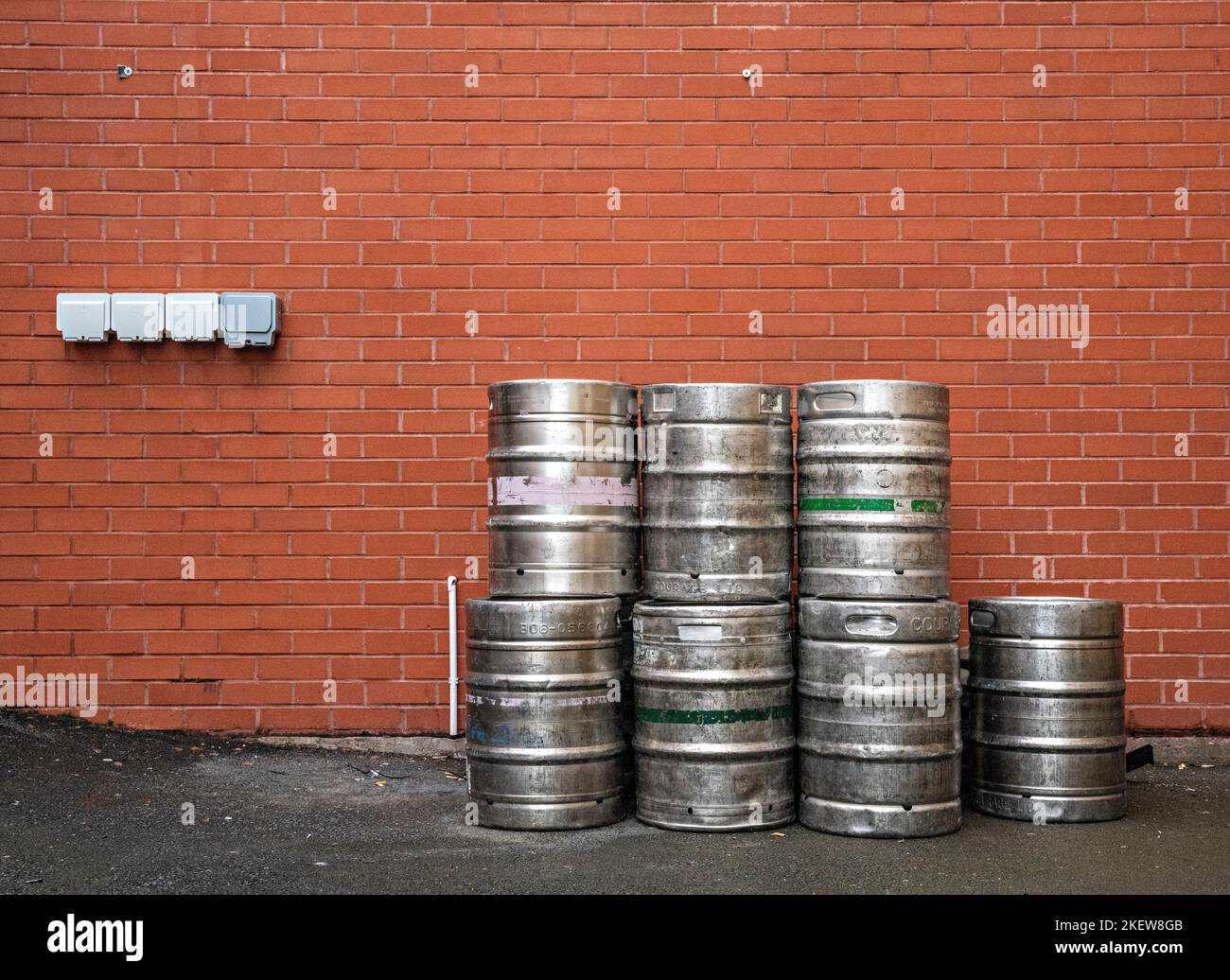 Barrels stacked against red brick wall Stock Photo