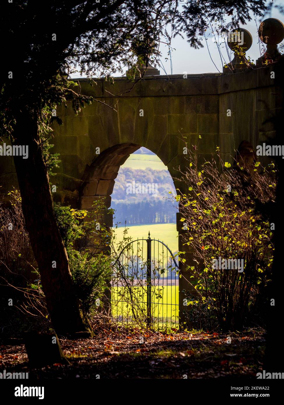Looking out through one of the arches of the Archer's Hill Gate towards the parkland of Wentworth Castle Gardens. UK Stock Photo