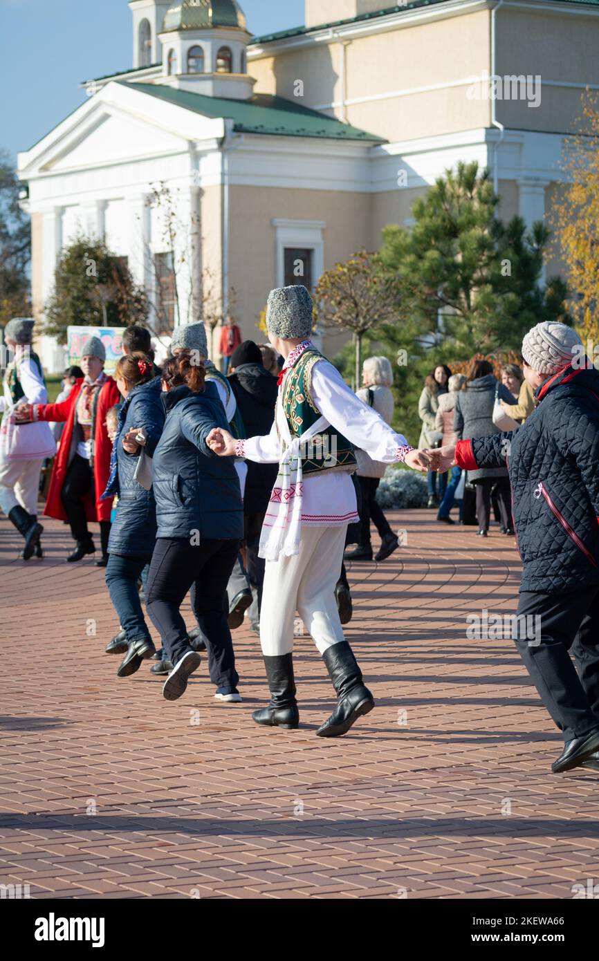 Bendery, Moldova - November 12, 2022: People dance Moldovan dance. Men and women in national costumes dance the beautiful Moldavian chora dance on eve Stock Photo