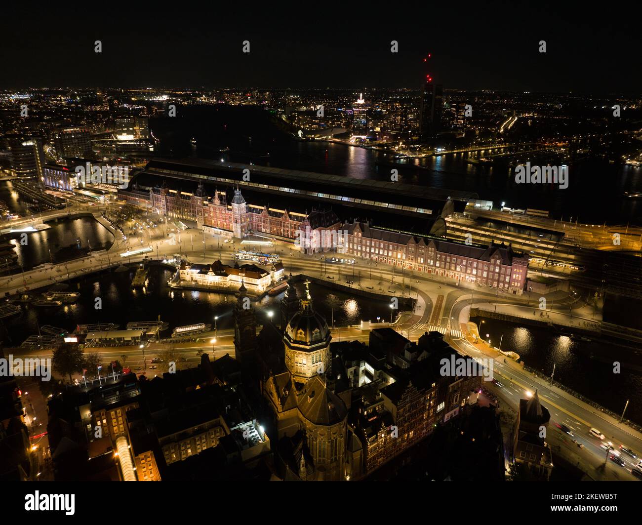 Amsterdam city center skyline by night aerial drone overhead view. Amsterdam Centraal, Ij, Oosterdok, Prins Hendrikkade, public transport, traffic at Stock Photo