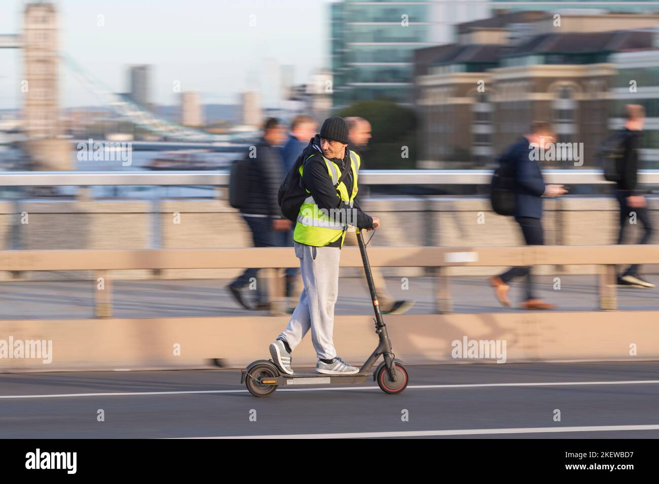 A man riding an escooter across London Bridge, during the rush hour