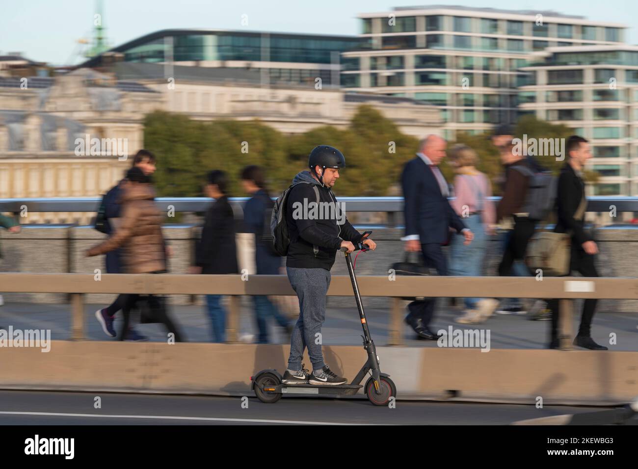 A man riding an escooter across London Bridge, during the rush hour