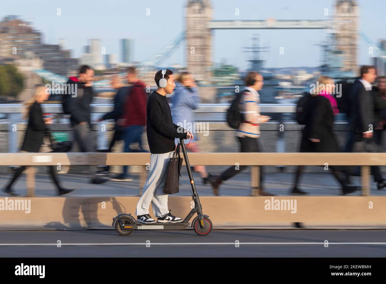 A man riding an escooter across London Bridge, during the rush hour