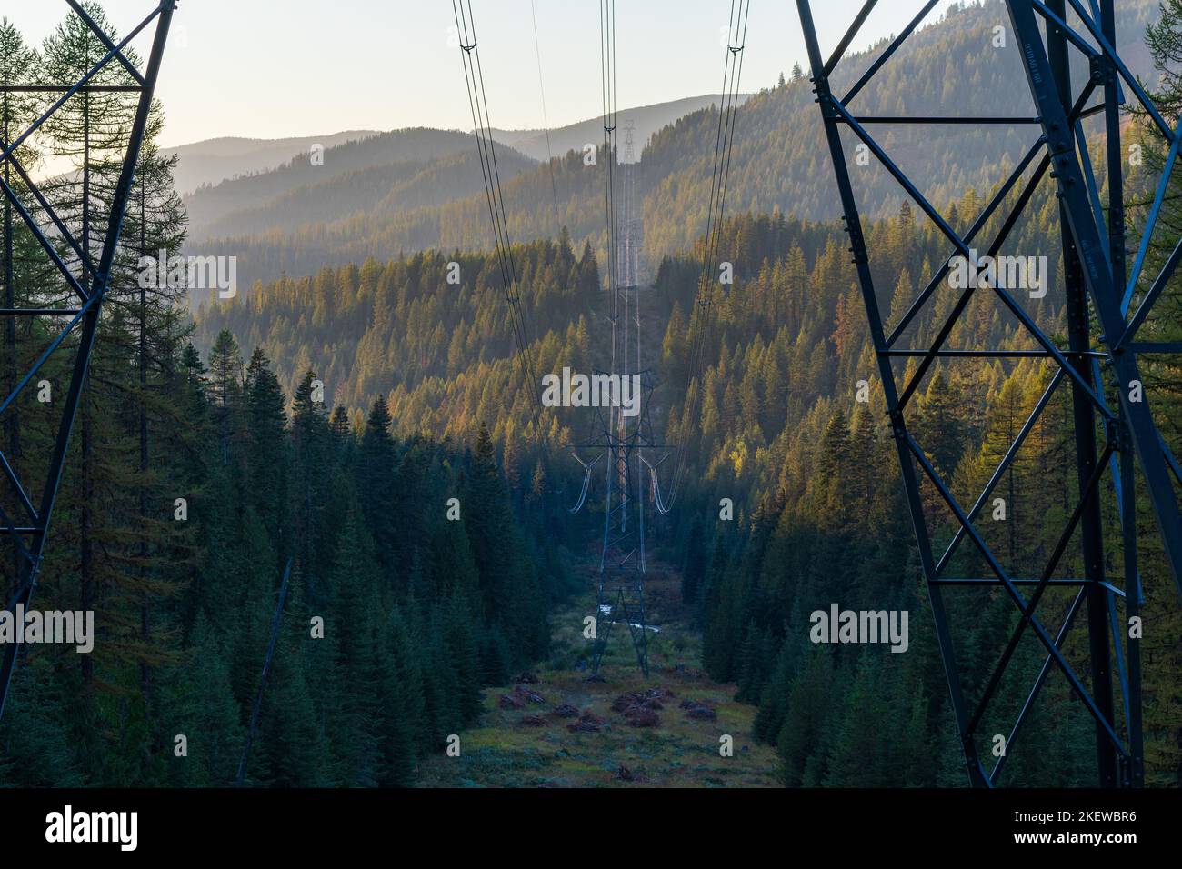 High Voltage Power Lines cross a mountain top and valley. Stock Photo