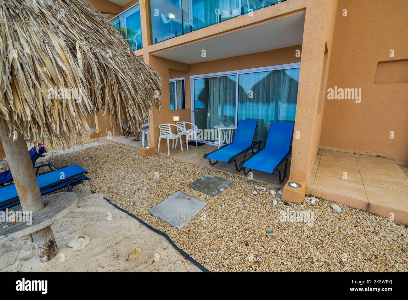 View of hotel patio with sun beds and reflection in window of beach  Atlantic ocean in background. Aruba. Stock Photo