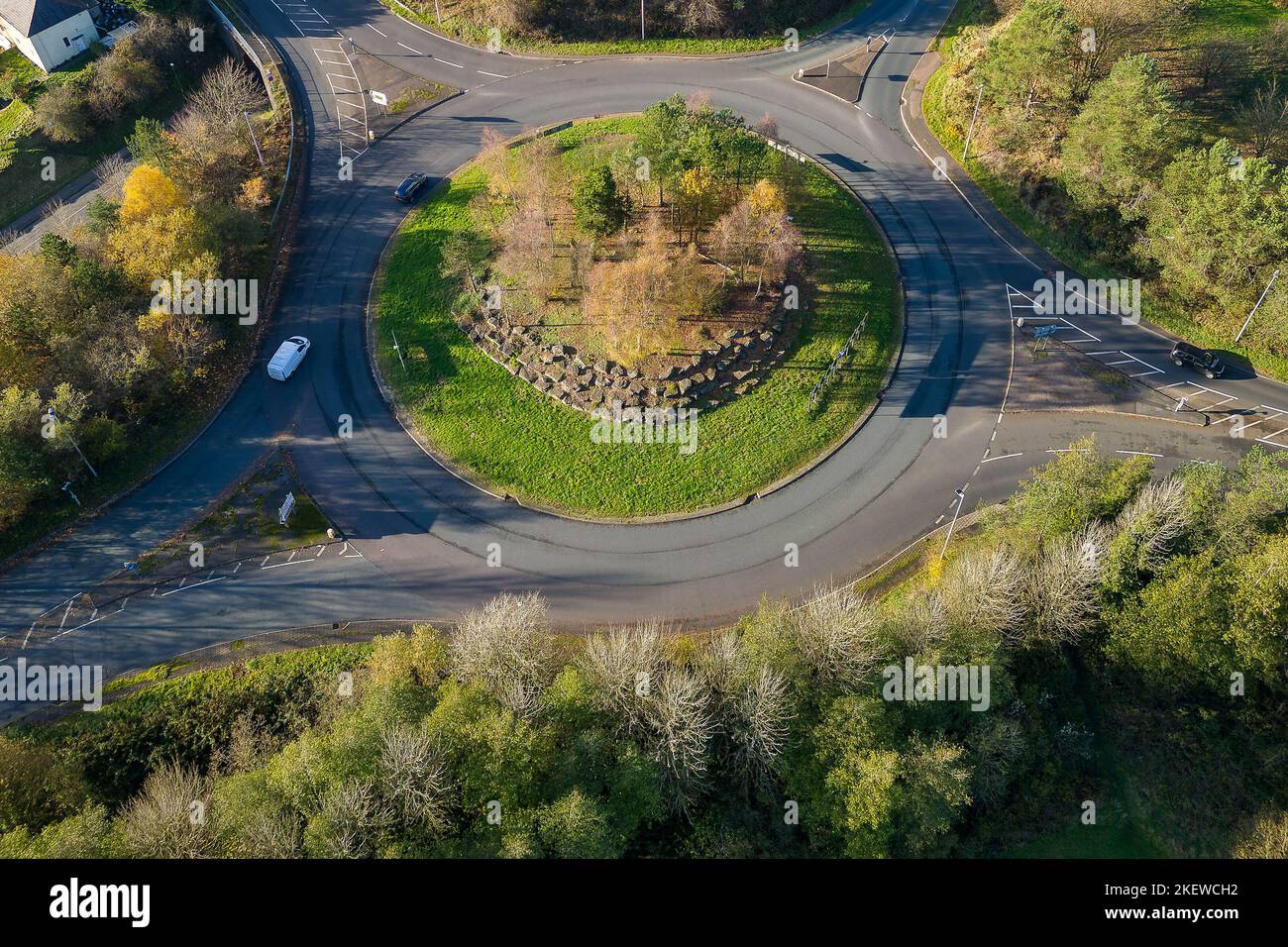 Aerial view of a small traffic roundabout on a rural road with fall (autumn) colored trees around. Stock Photo