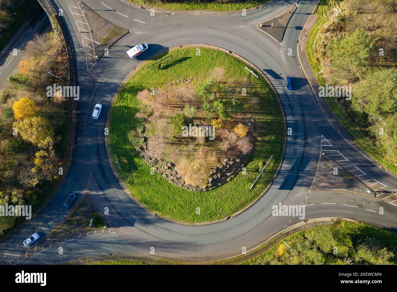 Traffic using a small roundabout surrounded by autumn colour trees ...