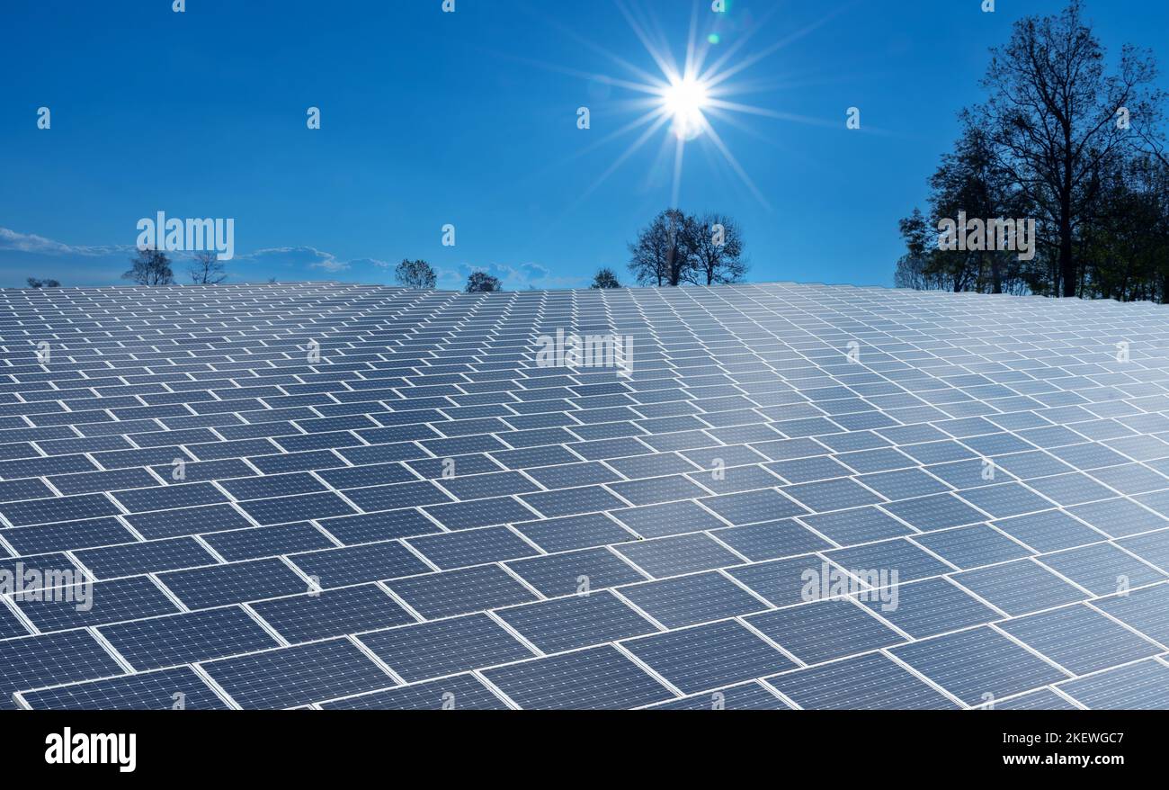 Vast surface of Solar Panels on blue sky with sun shining, Photovoltaic solar cells energy farm for production of clean renewable energy from the sun' Stock Photo