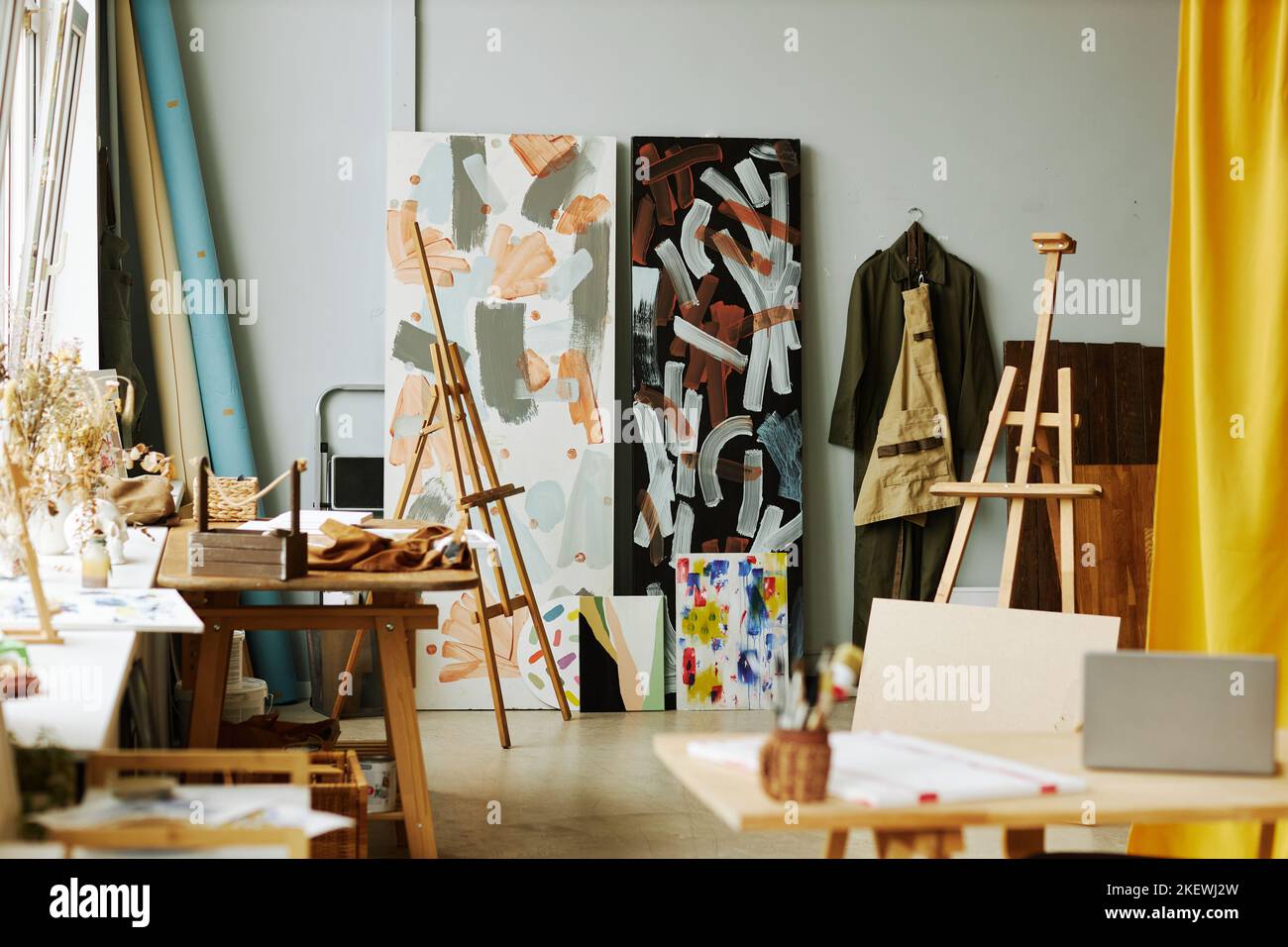 Part of spacious studio of arts with wooden easels, paintings on